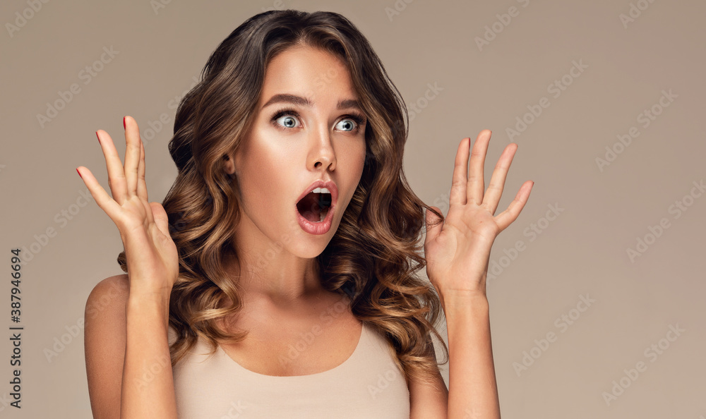 Beautiful shocked and surprised woman screaming and looking to the side presenting your product . Curly hair girl amazed . Expressive facial expressions . Beauty and cosmetology Beautiful shocked and surprised woman screaming and looking to the side presenting your product . Curly hair girl amazed . Expressive facial expressions . Beauty and cosmetology