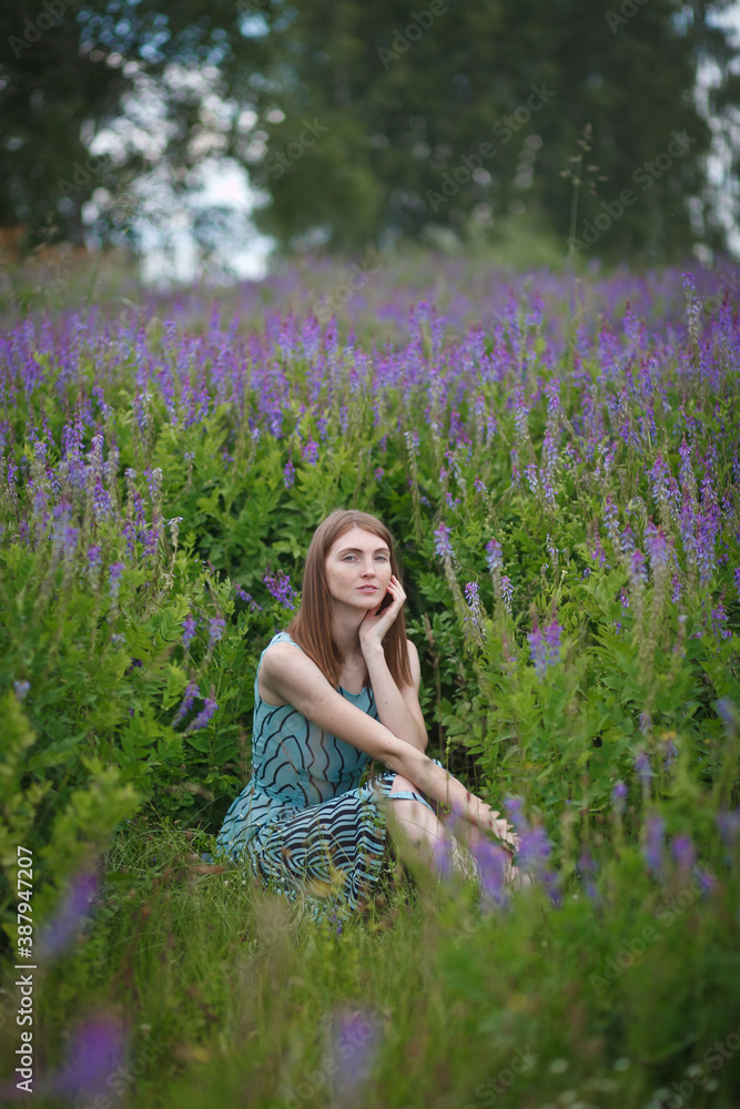 beautiful red-haired girl walking in a field of purple flowers beautiful red-haired girl walking in a field of purple flowers
