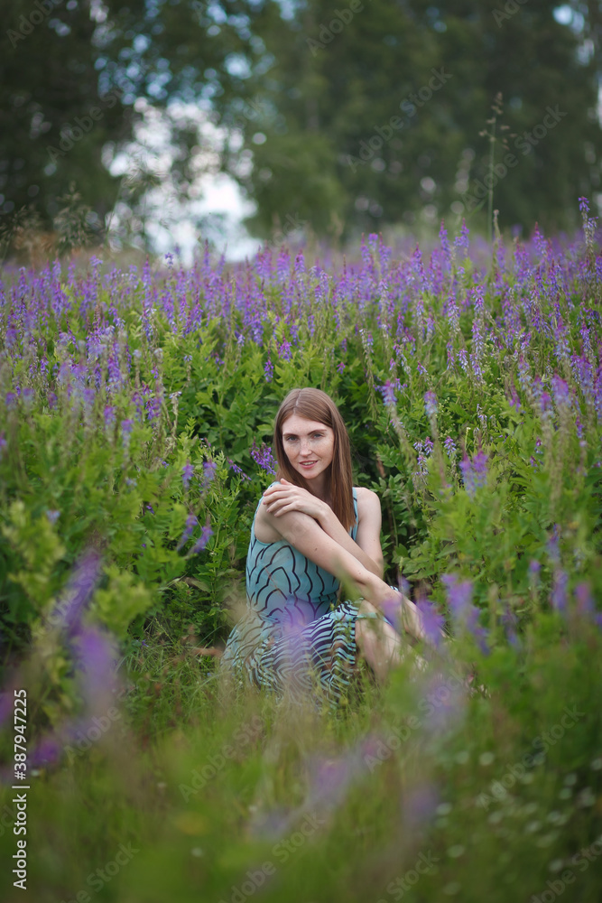 beautiful red-haired girl walking in a field of purple flowers beautiful red-haired girl walking in a field of purple flowers