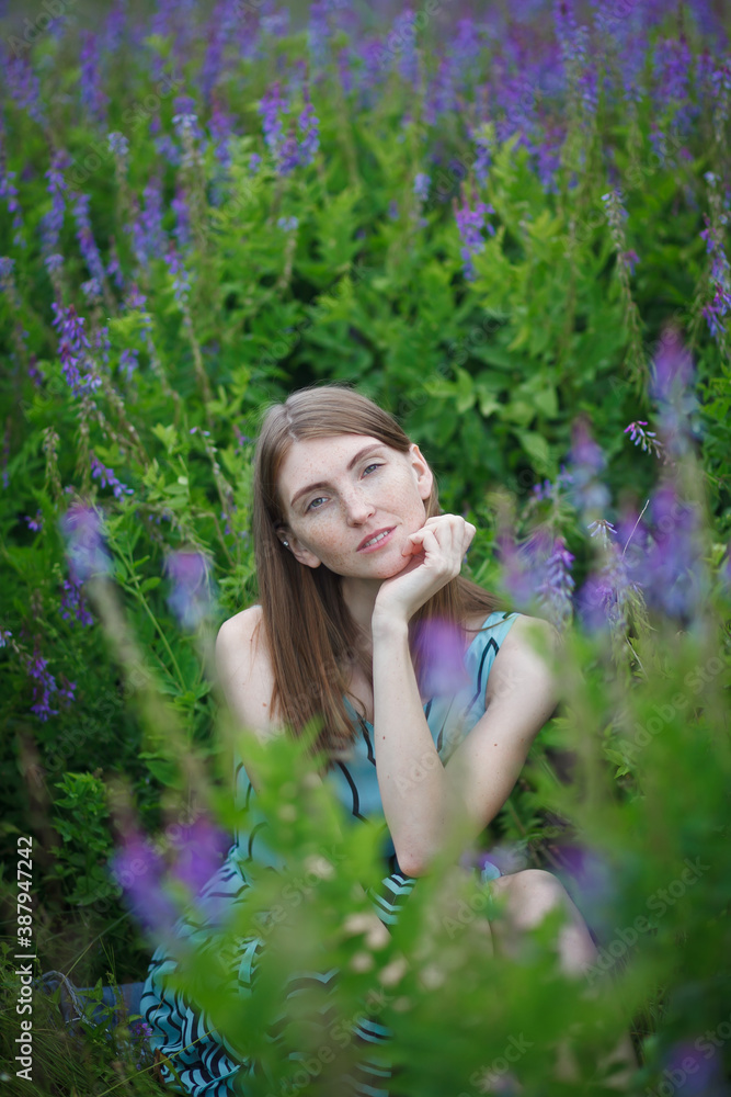 beautiful red-haired girl walking in a field of purple flowers beautiful red-haired girl walking in a field of purple flowers