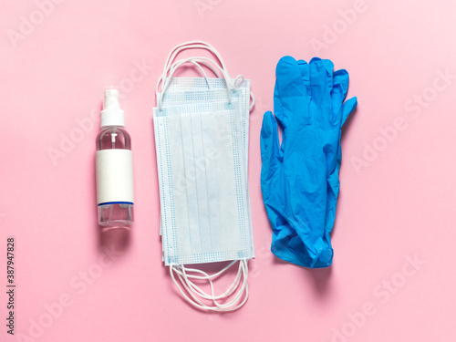 Medical protective mask, latex gloves, hand sanitizer on a pastel pink background. Individual, disposable hygiene equipment. Quarantine healthcare, hygiene and coronavirus protection concept.