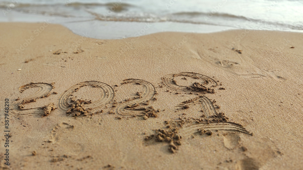 Obraz premium New Year 2021 and wave erasing 2020 year written in the sand