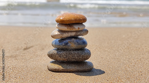 zen stones laid out by hand lying on sand of sea beach