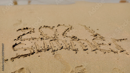 word handwritten summer 2021 on yellow sandy beach