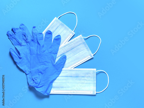 Medical protective masks and latex gloves on a blue background. Individual, disposable hygiene equipment. Quarantine healthcare, hygiene and coronavirus protection concept.