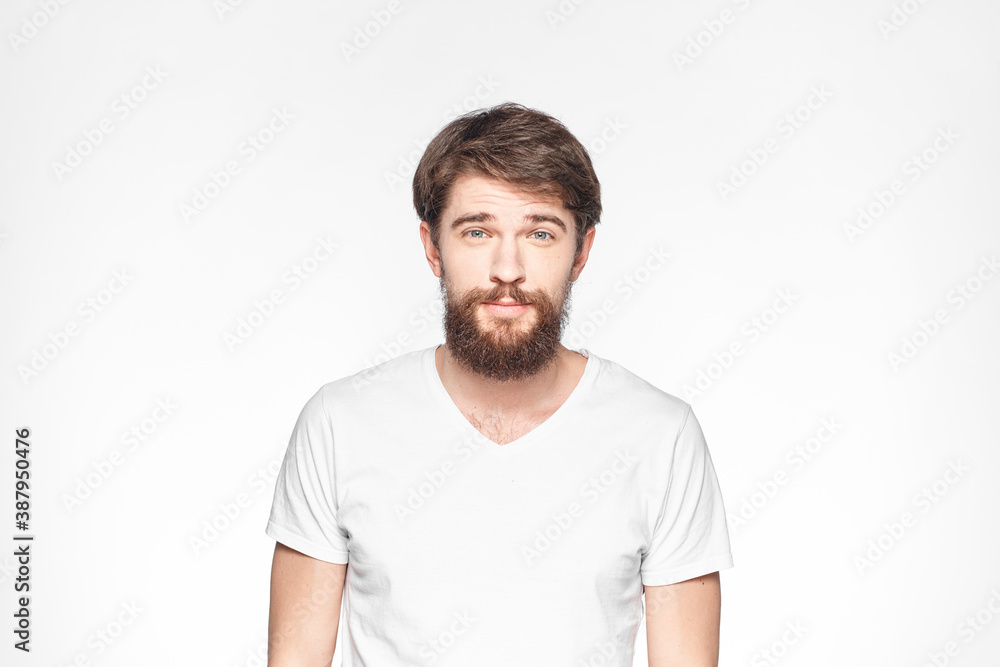 Bearded man in white t-shirt gesture with hands emotions light background Bearded man in white t-shirt gesture with hands emotions light background