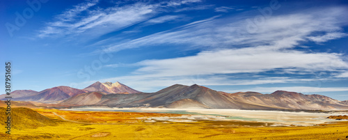 Panoramic landscape on the altiplao in Northern Chile with volcanoes and saltlake under clear sky with some clouds