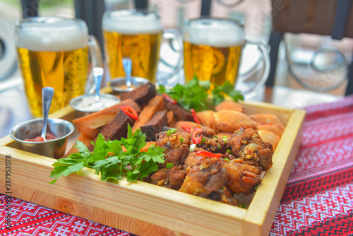 A large plate with a wide selection of snacks for beer. Three beer glasses in the background.