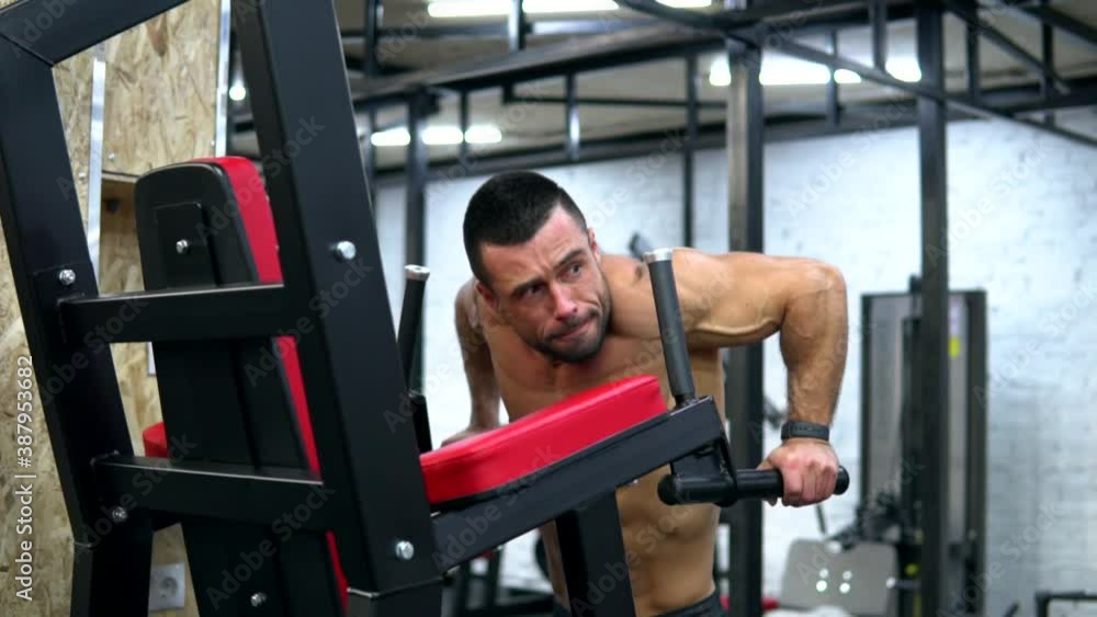 Athletic shirtless bodybuilder man, doing dips exercise on a parallel bars in a gym. Body weight triceps workout. Panorama middle shot. Athletic shirtless bodybuilder man, doing dips exercise on a parallel bars in a gym. Body weight triceps workout. Panorama middle shot.