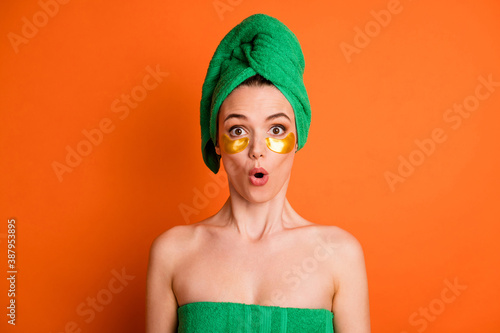 Fototapeta Photo portrait of shocked woman with golden eye patches isolated on vivid orange