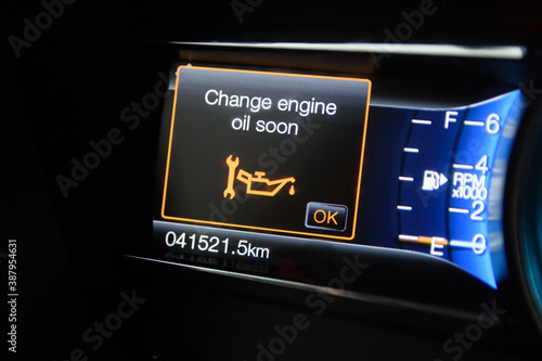 The on-board computer of a modern car with color infographics warns the driver about changing engine oil soon. Color multi-function car display