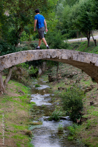 Hombre cruzando un puente medieval