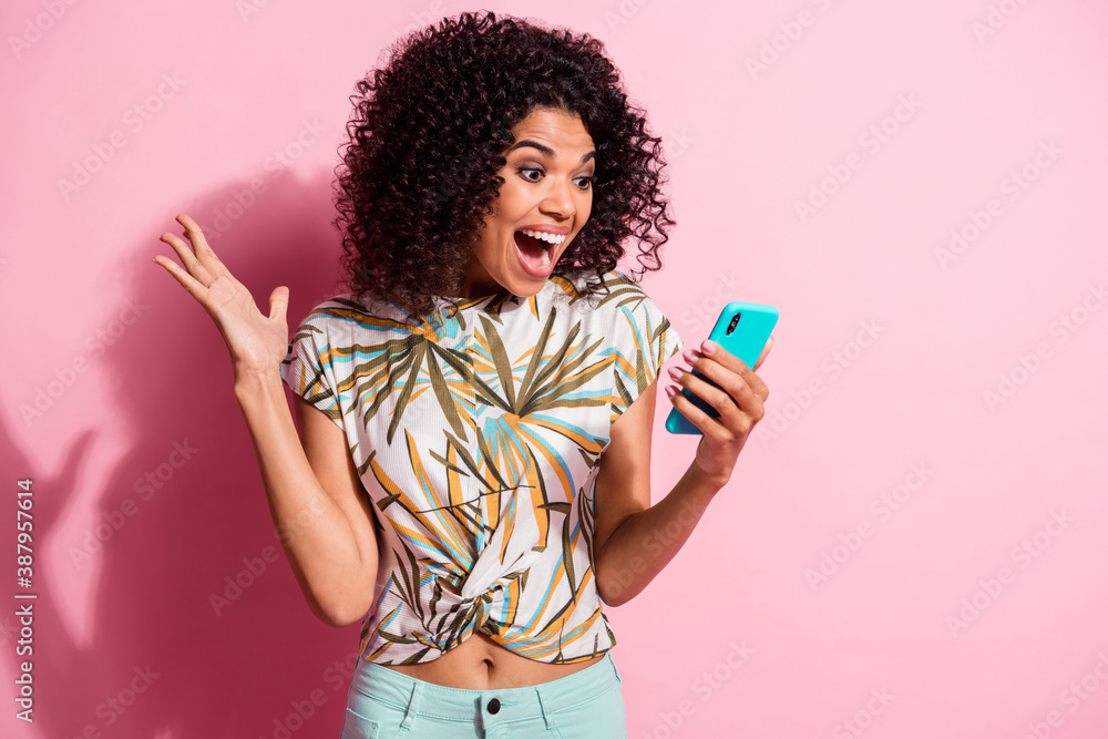 Photo portrait of shocked screaming girl unexpectedly winning holding phone in hand isolated on pastel pink colored background - obrazy, fototapety, plakaty 