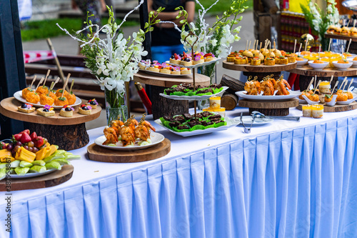 Small cakes  fruit  shrimp skewers and decorations on the white table