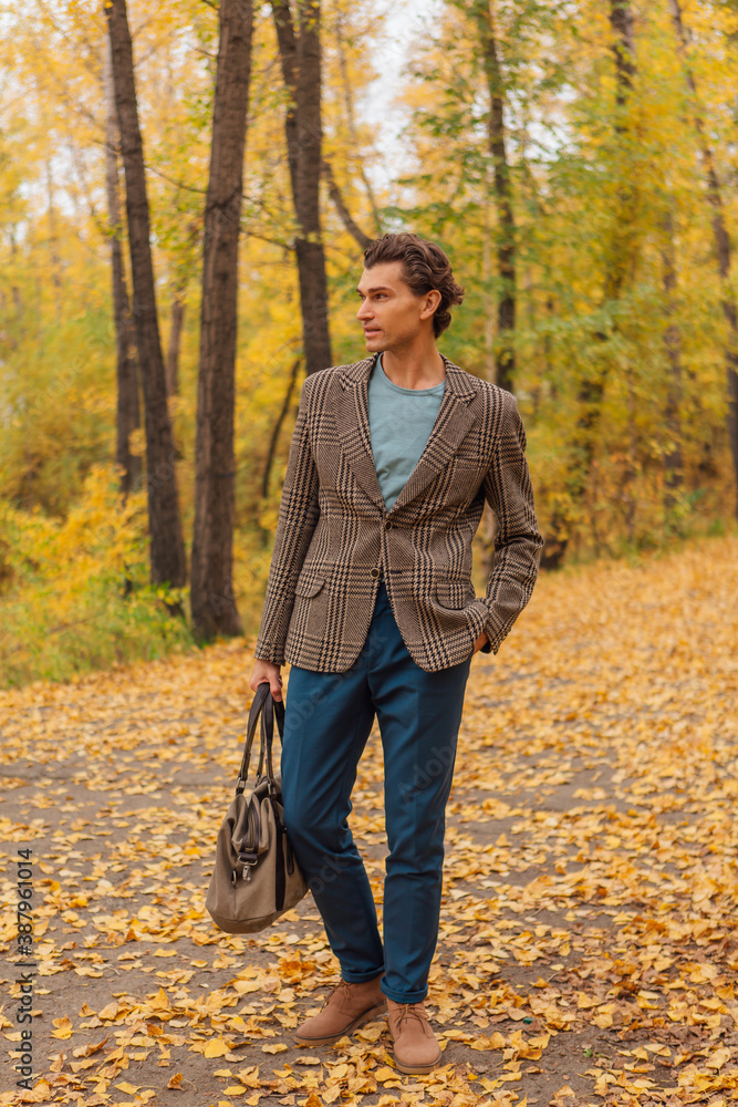 Tall handsome man with a bag on the autumn alley Tall handsome man with a bag on the autumn alley