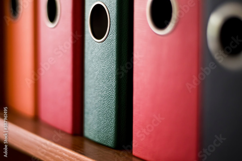 Colorful files on a shelf to assort the documents in the office. Red, orange and green plastic folders.