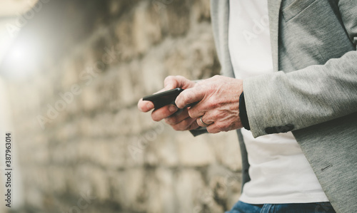 Man standing against a wall and using mobile phone