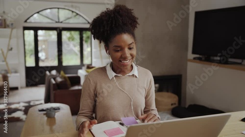Portrait of a young woman sitting at her desk talking on video call while looking at computer screen from home photo
