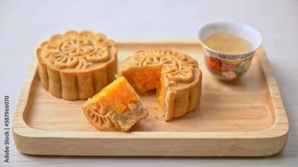 Chinese moon cake durian and egg yolk flavour with tea on wood plate Chinese moon cake durian and egg yolk flavour with tea on wood plate