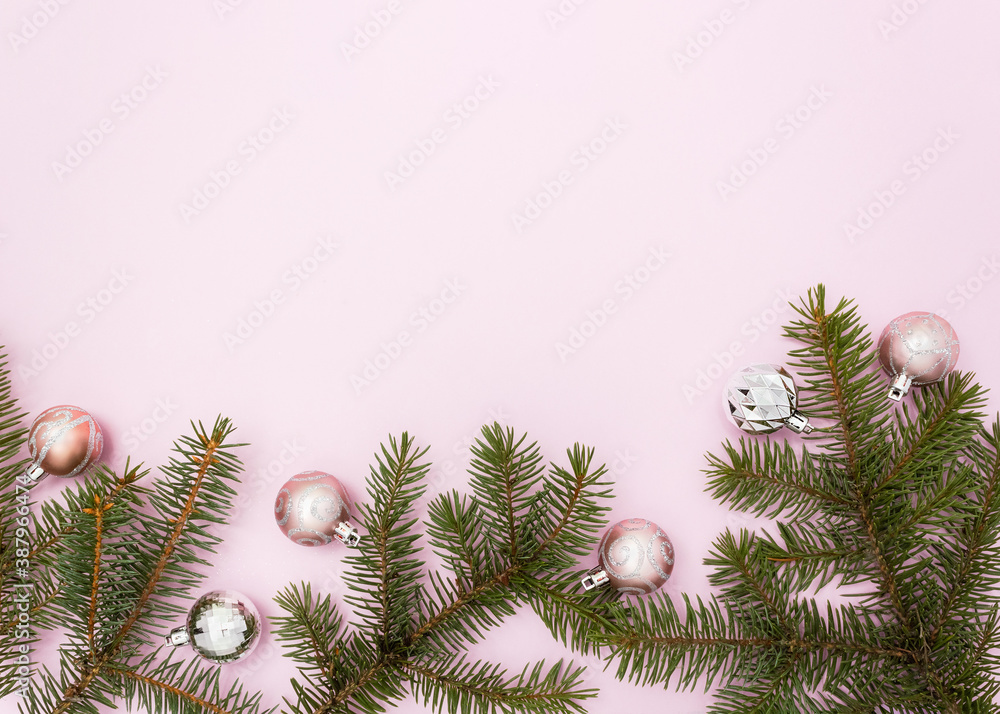 Christmas decoration balls and fir branches on pink background. New Year's card for beauty salons. Flat lay, place for text.