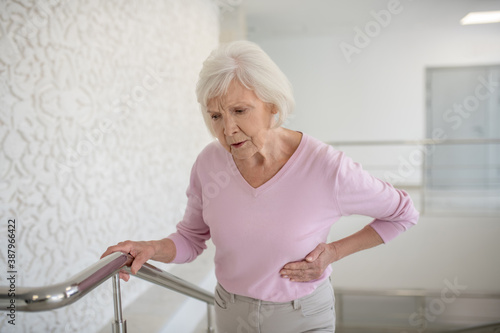 Elderly woman in a pink shirt suffering from pain