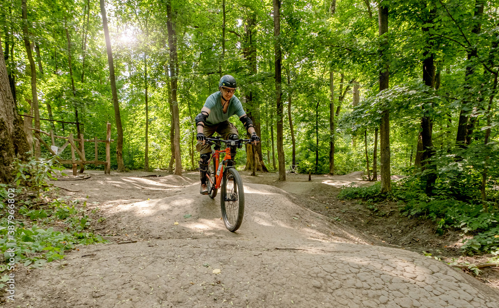 Naklejka premium Man riding bicycle on forest road