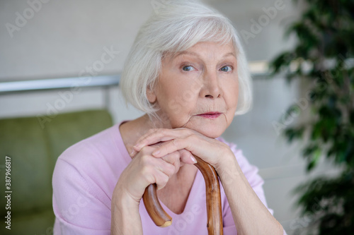 Grey-haired womanwith walking stick looking serious and thoughtful photo