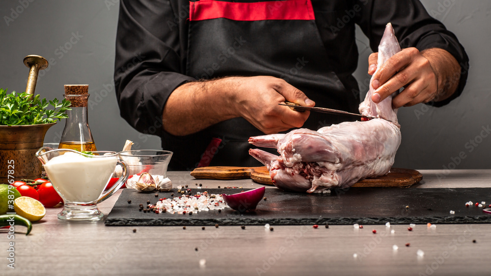 Chef salts carcass of fresh rabbit. Preparing Raw rabbit meat. cooking process, Food recipe background. space for text