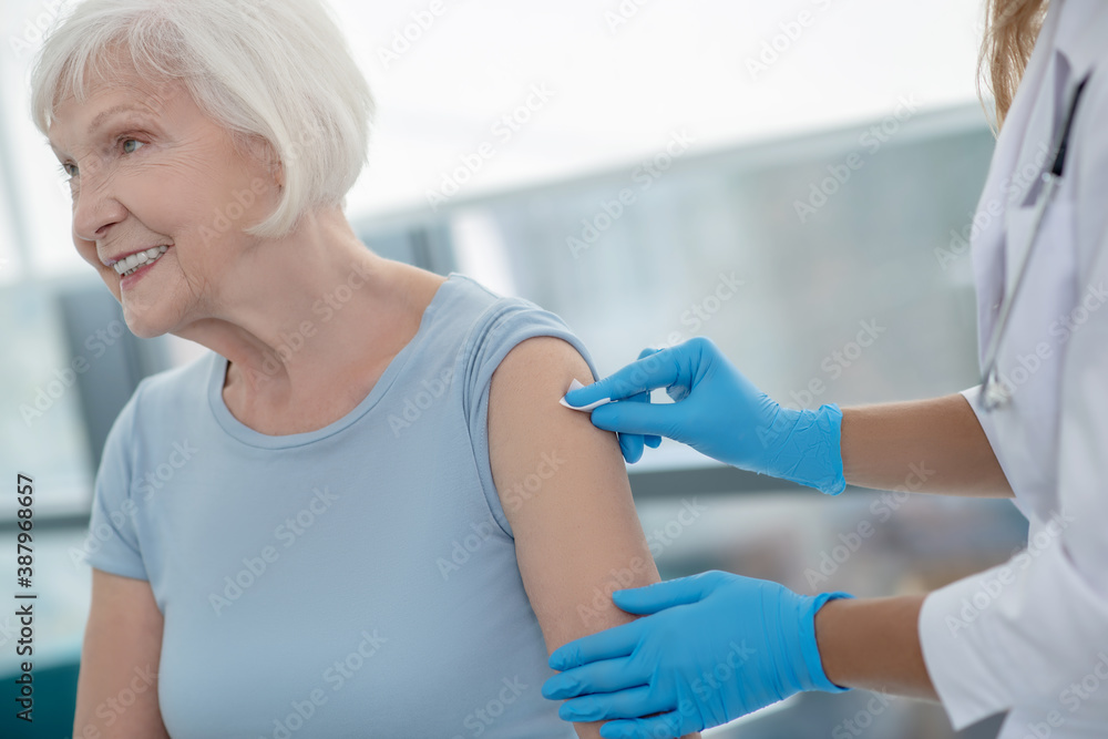 Nurse making an injection to an elderly smiling woman Nurse making an injection to an elderly smiling woman