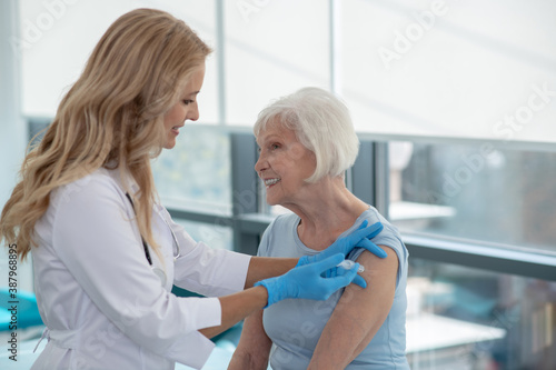 Long-haired smiling nurse making vaccination to an elderly woman © zinkevych