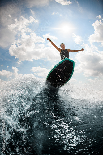 Photography woman jumping on the board wake surfing on the river against the cloudy sky