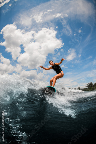 view of woman who jumping on the board wake surfing on the river against the cloudy sky