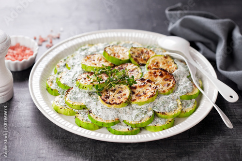 Grilled zucchini slices with coconut yogurt sauce, dill and garlic, selective focus