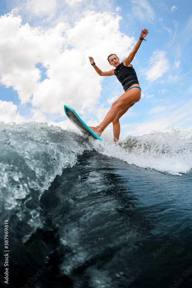 Side view of woman who jumping on the board wake surfing on the river against the cloudy sky Side view of woman who jumping on the board wake surfing on the river against the cloudy sky