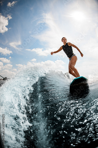 view of woman who rides on the wake surf on high wave against blue sky