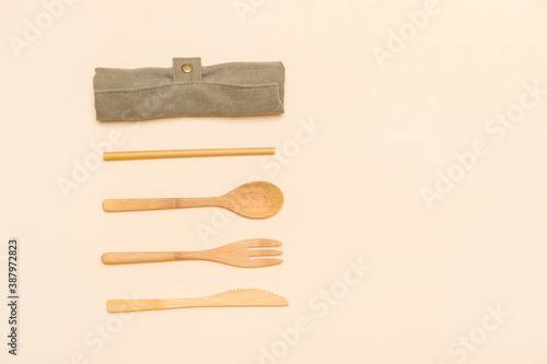 Set of Eco friendly bamboo cutlery on camel color background. Plastic free concept. Close-up, top view.