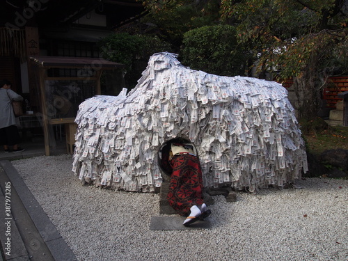 An Asian woman in a traditional Japanese kimono walks through a hole in a monument to break a bad relationship and make a good one, Yasui Konpira-gu Shrine, Kyoto, Japan photo