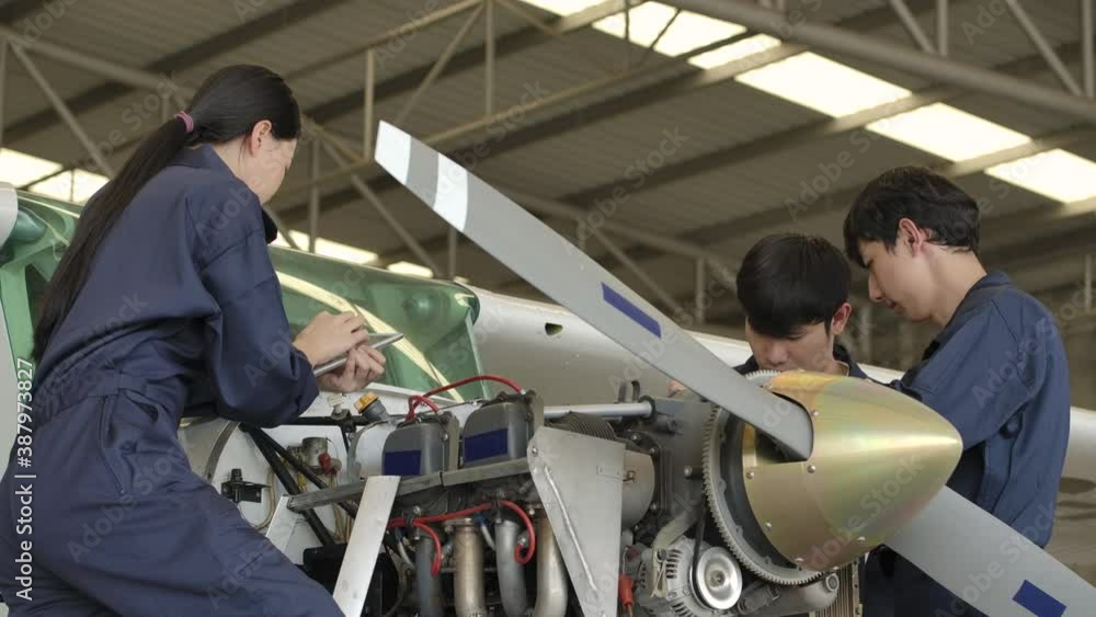 Group of young asian aviation maintenance engineer doing a pre flight checkup or maintenance on a small engine aircraft using digital tablet in hangar. Transportation and Technology concept. Group of young asian aviation maintenance engineer doing a pre flight checkup or maintenance on a small engine aircraft using digital tablet in hangar. Transportation and Technology concept.