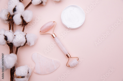 Rose quartz jade roller on pink background. Anti age, lifting and toning treatment at home.