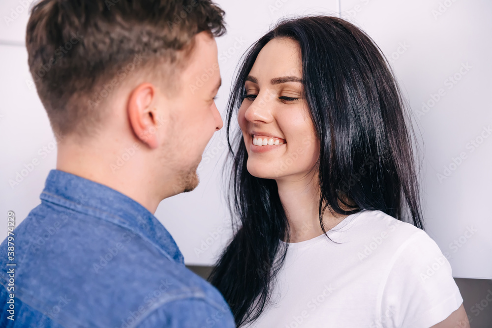 adult couple embracing and smiling at kitchen and looking into eyes adult couple embracing and smiling at kitchen and looking into eyes