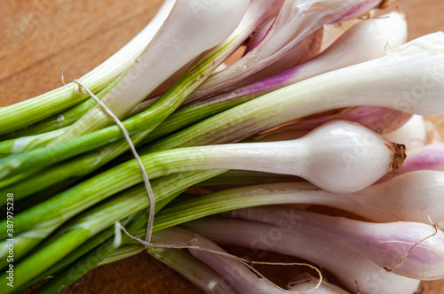 A bunch of little white and pink onions, cebollitas, on a wooden cuttingboard photo