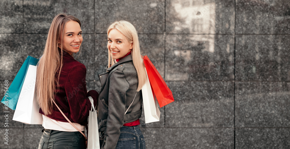 Cheerful girlfriends with shopping bags on street