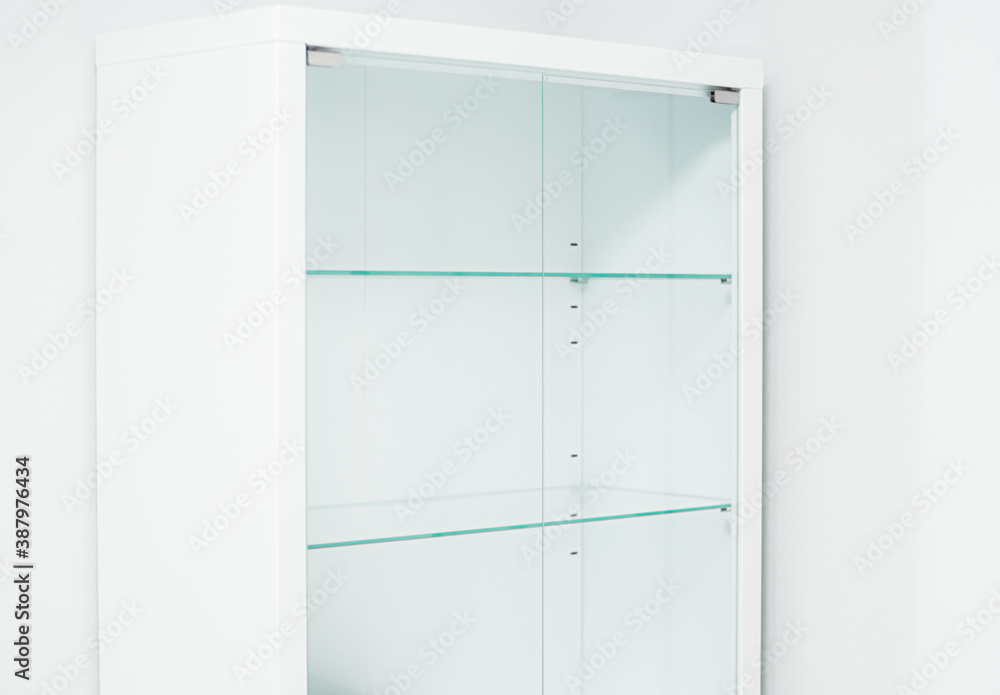White new empty cabinet with thin glass shelves. Minimalistic light cupboard. Medical room. Close-up White new empty cabinet with thin glass shelves. Minimalistic light cupboard. Medical room. Close-up