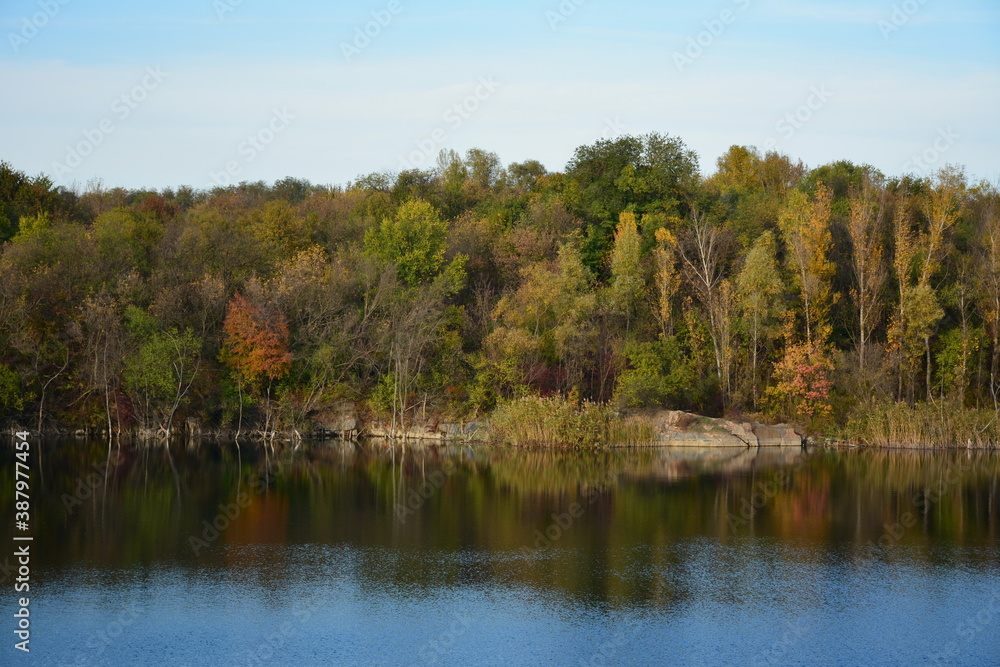 The trees in autumn clothes and their reflection in the water.