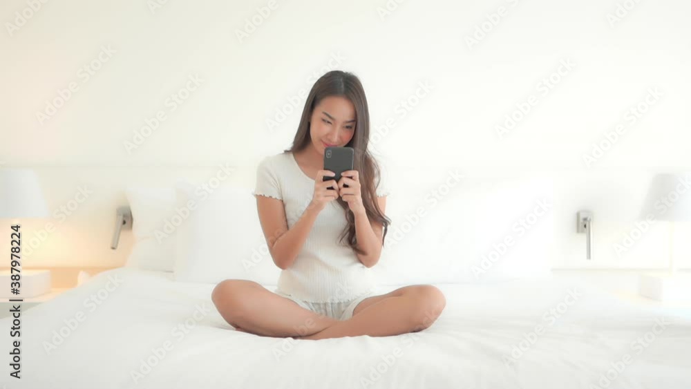 Girl Using Smartphone on the Bed, Bright White Dreamy Bedroom Scene Girl Using Smartphone on the Bed, Bright White Dreamy Bedroom Scene