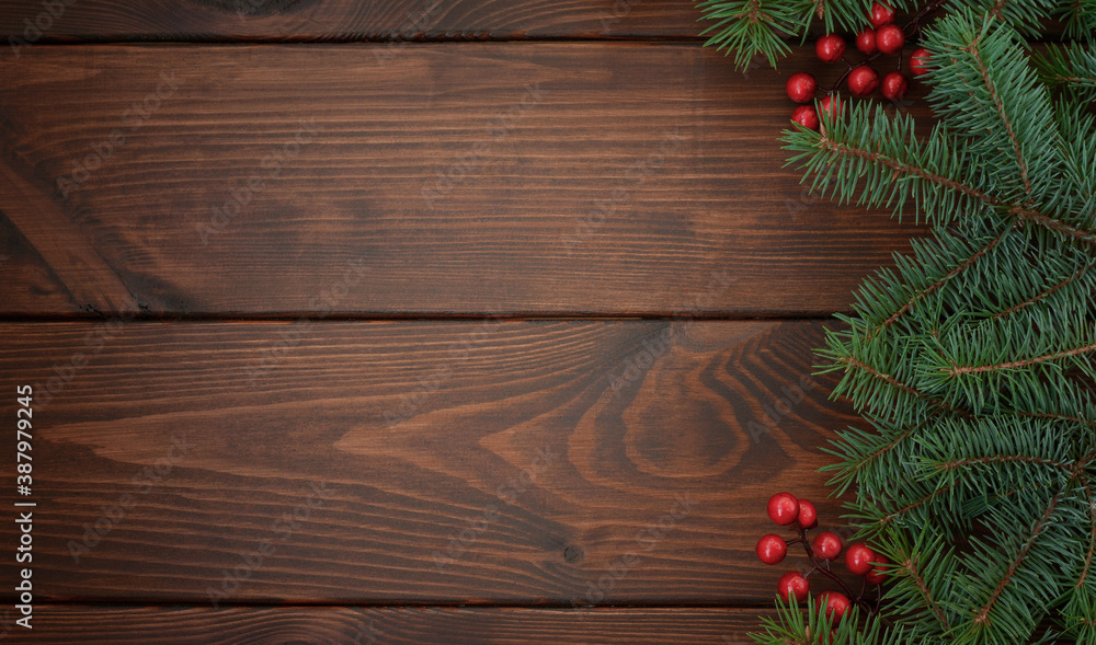 Pine branches with red berries on a wooden background. Christmas background. Happy New Year! Copy space for your text.