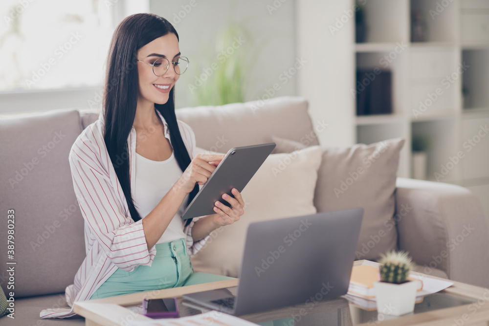 Photo of young business woman hold tablet typing touchscreen wear glasses shirt in home workstation indoors Photo of young business woman hold tablet typing touchscreen wear glasses shirt in home workstation indoors