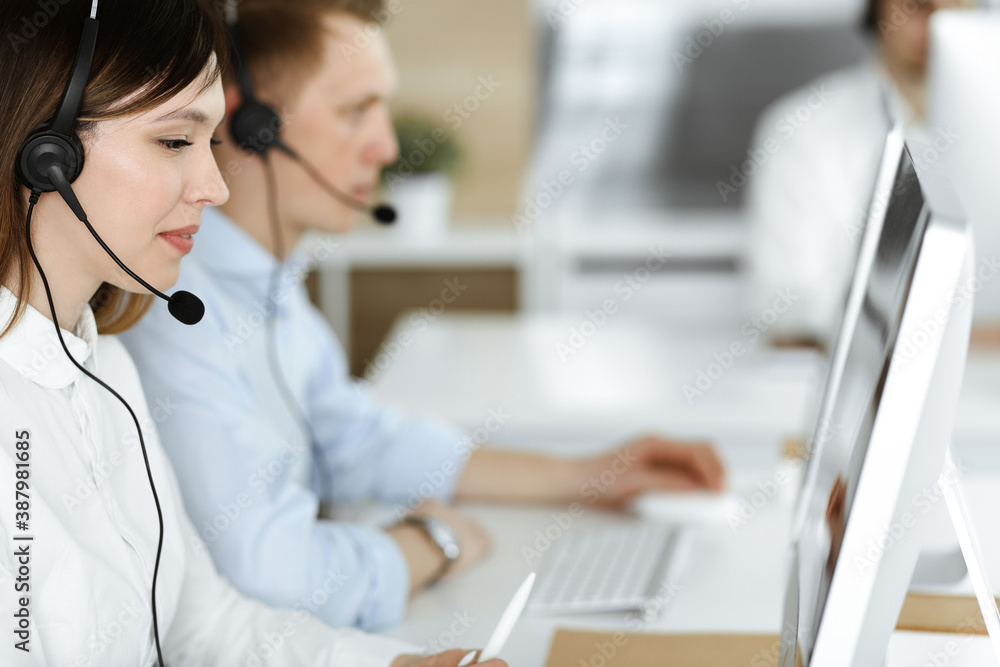 Group of diverse operators at work in call center. Beautiful asian woman sitting in headset at customer service office. Business concept Group of diverse operators at work in call center. Beautiful asian woman sitting in headset at customer service office. Business concept