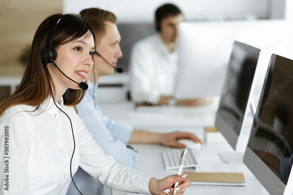 Group of diverse operators at work in call center. Beautiful asian woman sitting in headset at customer service office. Business concept Group of diverse operators at work in call center. Beautiful asian woman sitting in headset at customer service office. Business concept