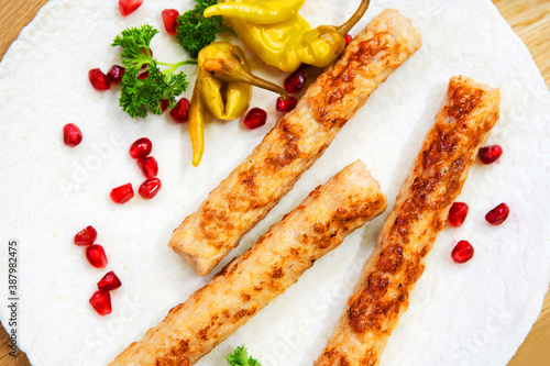 Meat sticks in batter on a white plate, decorated with pomegranate seeds and pepper with herbs. Fast cooking at home. Close-up